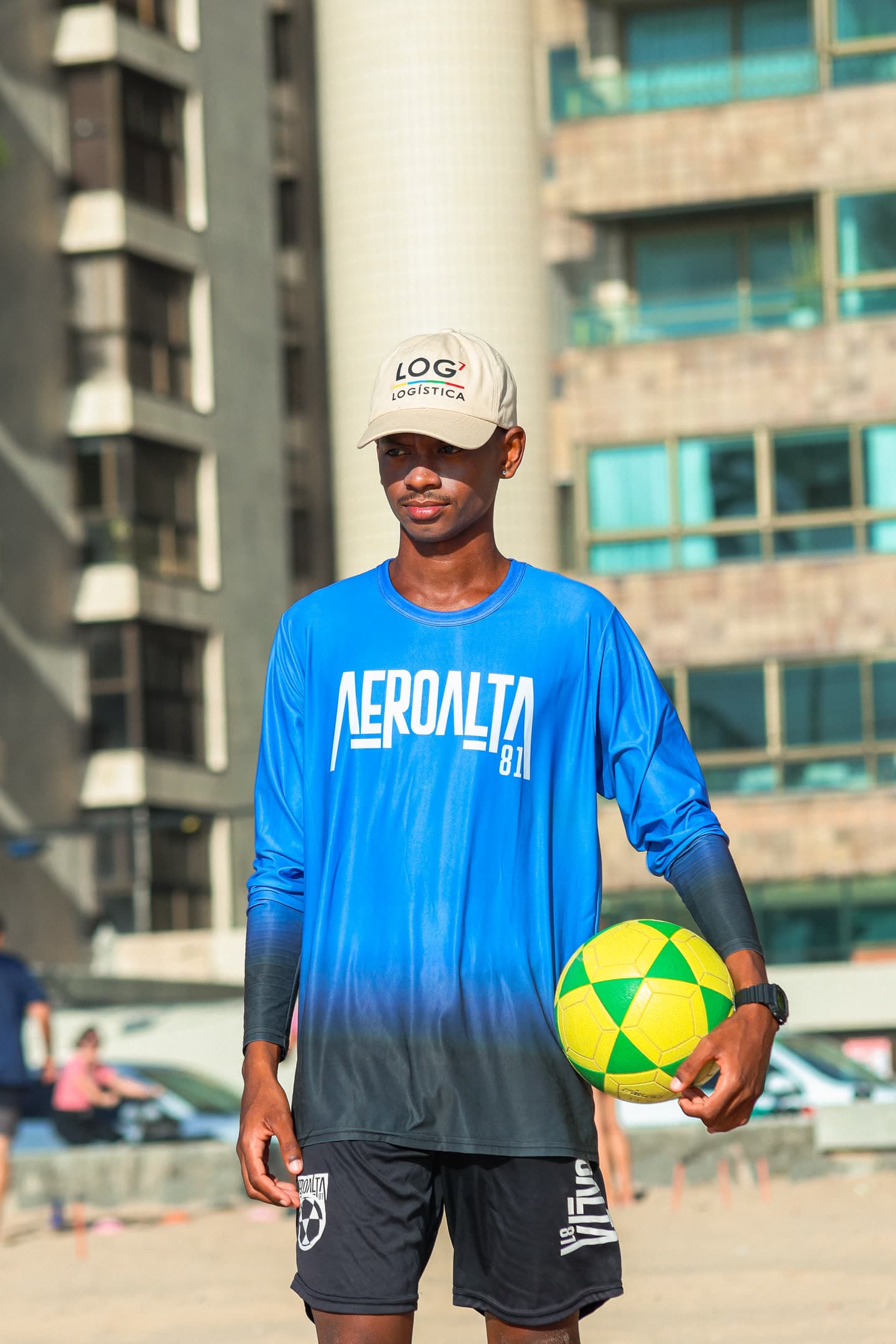 Atleta de camisa azul do Aero Alta 81 e boné, com uma bola verde e amarela sob o braço