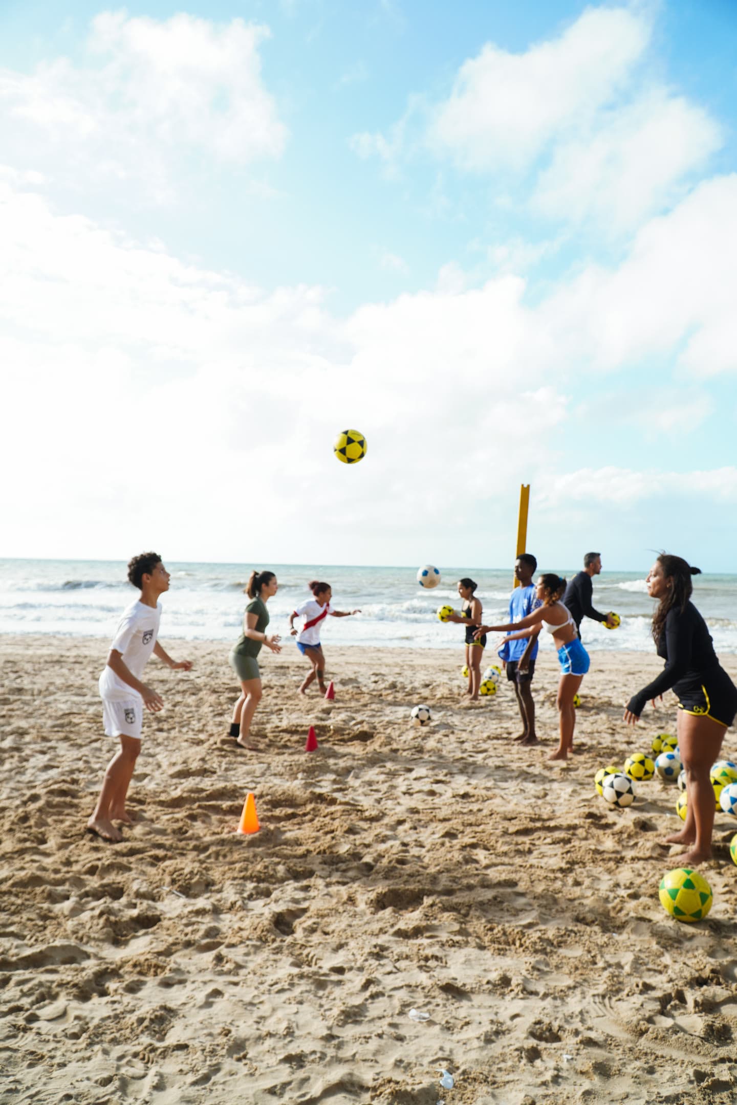 Turma de altinha em roda na praia de Boa Viagem, com bola no ar e o mar ao fundo