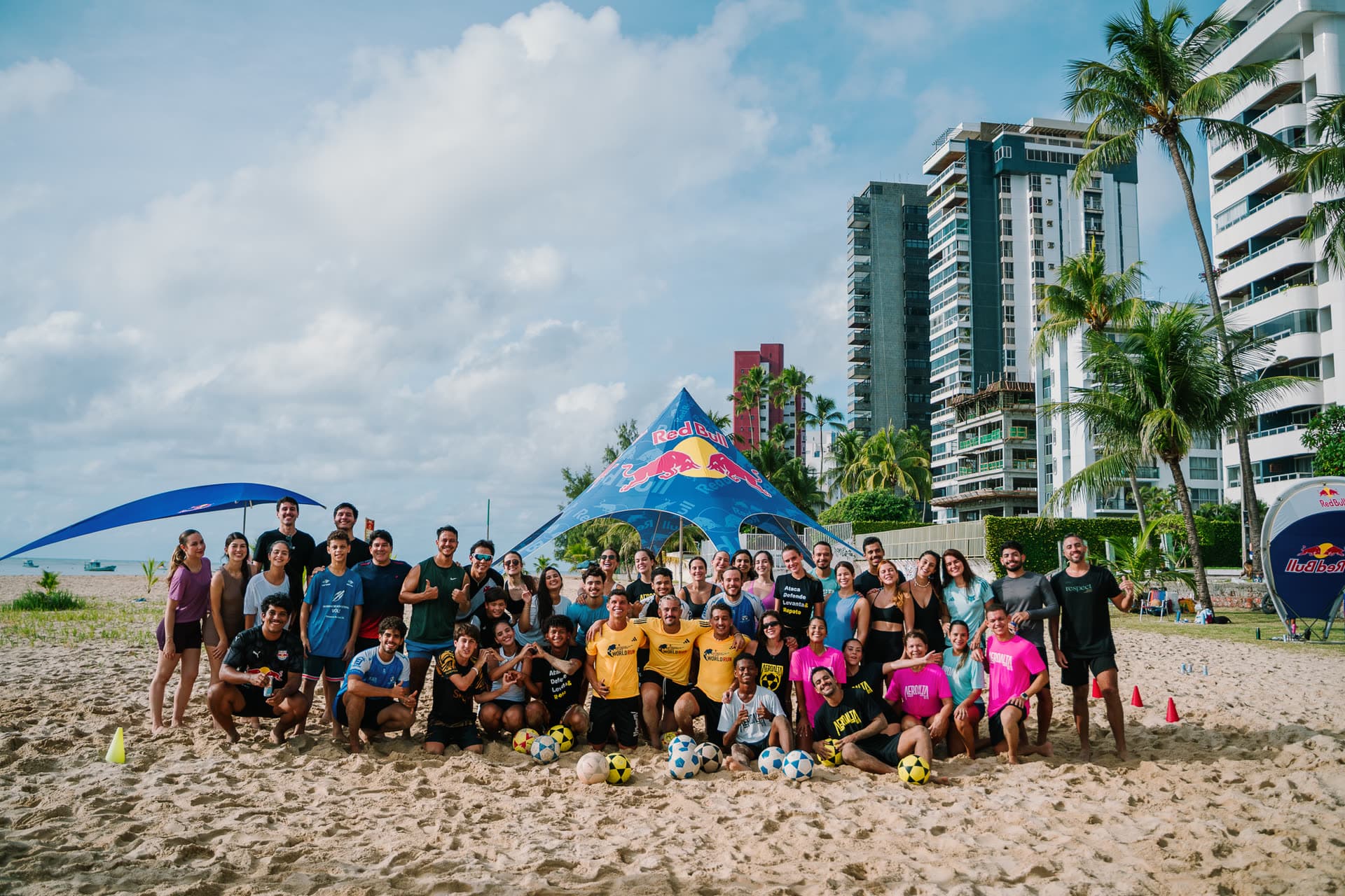 Foto da turma do Aero Alta 81 reunida na areia em frente à tenda do evento